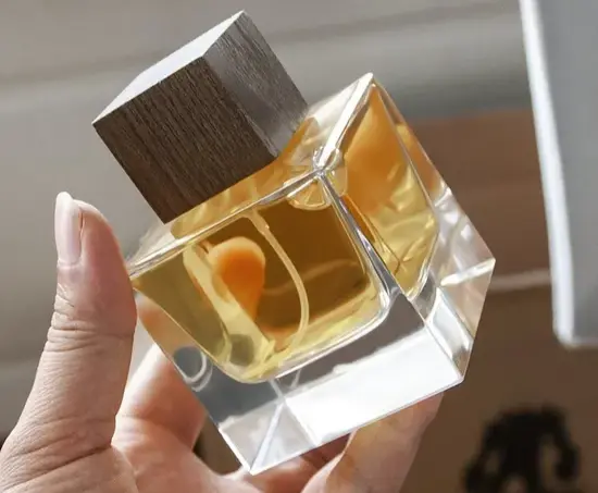 holding a bottle of perfume in one hand